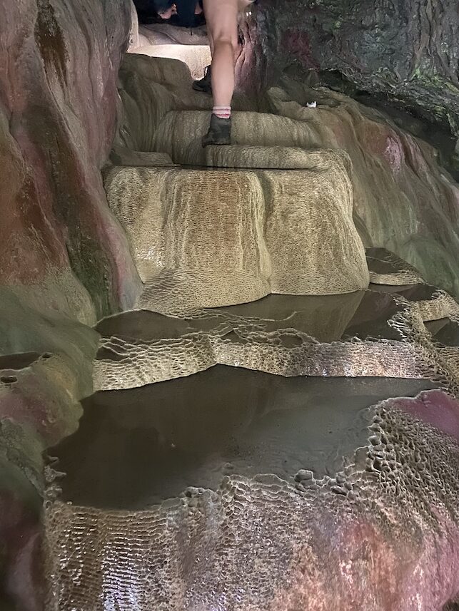 Lou, climbing up the "holy well" in St Cuthbert's Cave, Holywell Bay